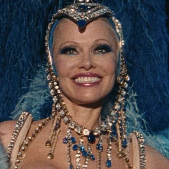 Pamela Anderson in una clip del film The Last Showgirl, sorridente nel costume blu con piume